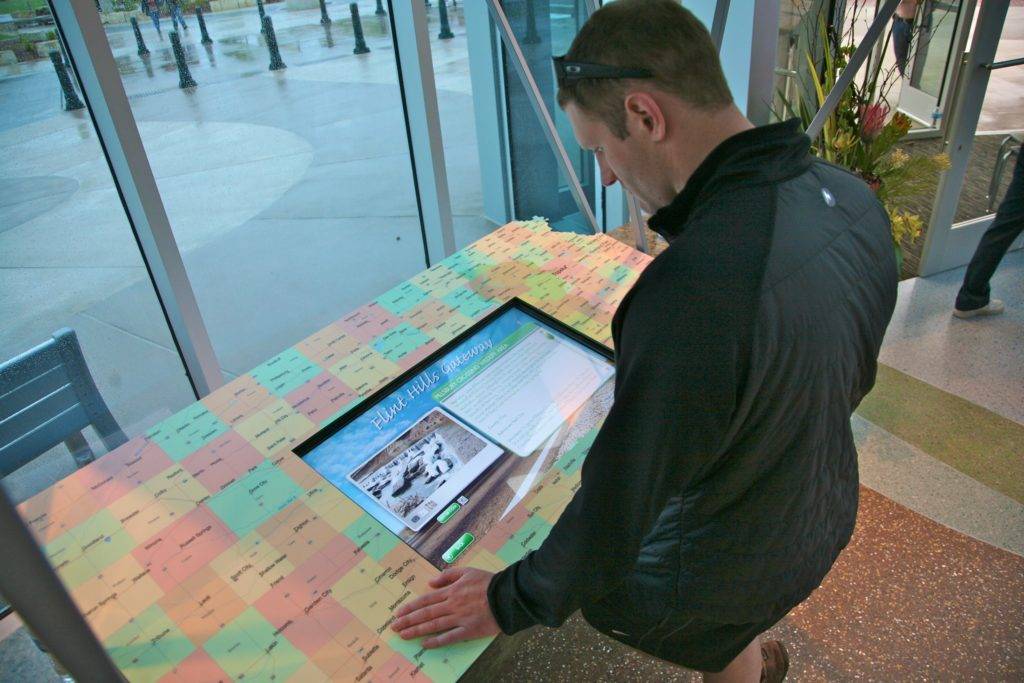 Man using a trip planner interactive, facing a window