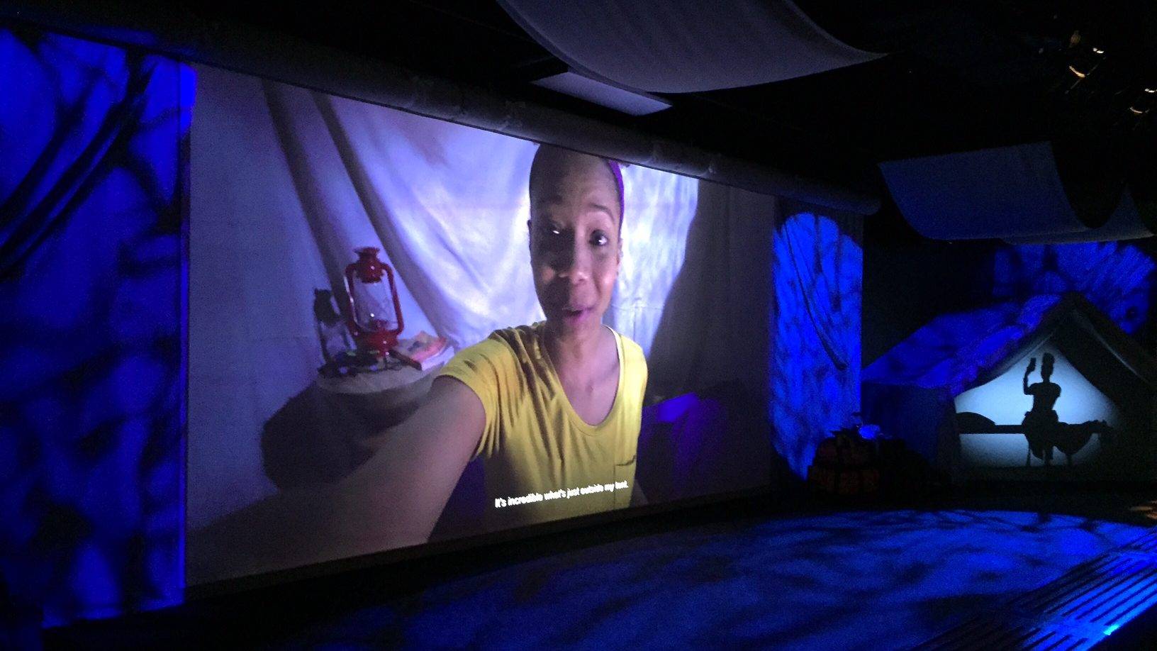 Exhibit screen shows a young girl vlogging in a tent