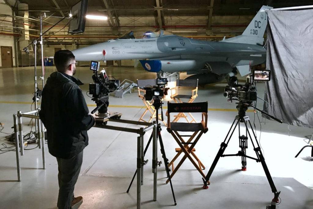 Camera equipment set up in front of a military plane