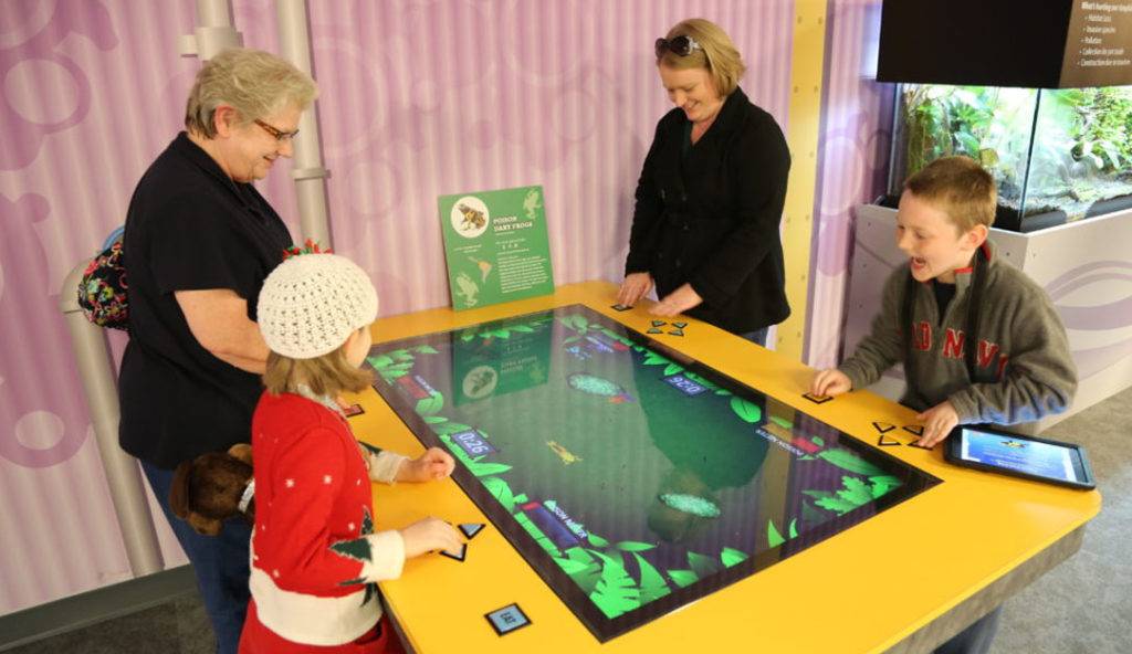 Families playing a game with physical buttons on a large interactive table