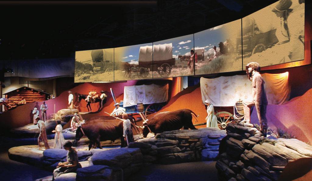Five-screen theater with western trail dioramas including wagons and oxen.