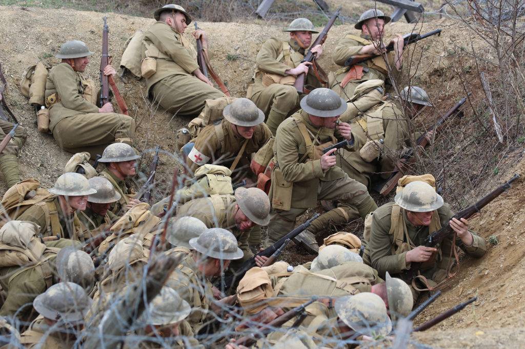 WWI battle reenactment actors crouching in a trench