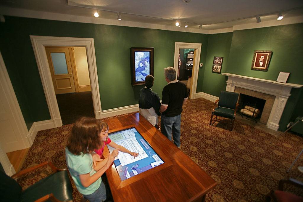 Visitors immersed in a physical recreation of the President's office. Children use an interactive table
