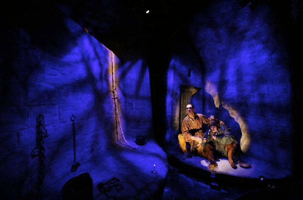 Life-sized pirate models in a disney-like exhibit, lit with blue and orange lighting