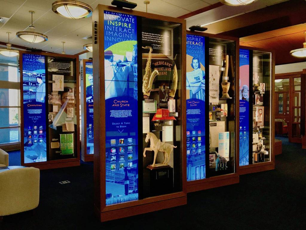 Digital display cases with an educational interactive display on the left and physical artifacts on the right