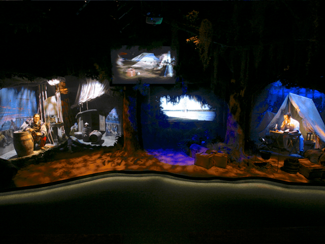 Scenic design with historical figures, theatrical lighting, and dramatic video production